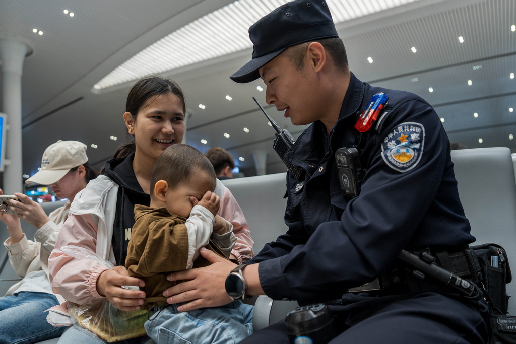 5月1日，乌鲁木齐铁路公安处乌鲁木齐站派出所民警向带小孩的旅客提示乘车安全。新华社发（叶帅 摄）